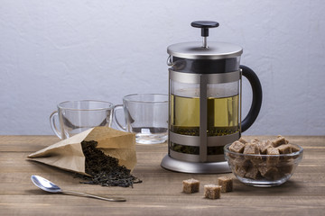 Hot tea in glass teapot and cup on wooden table.
