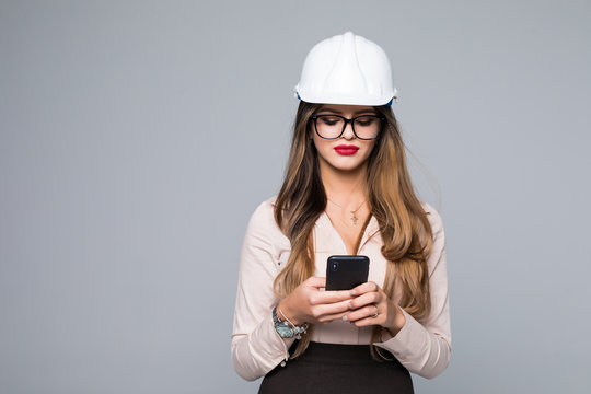 Picture of a beautiful female engineer sending a text message isolated on gray background