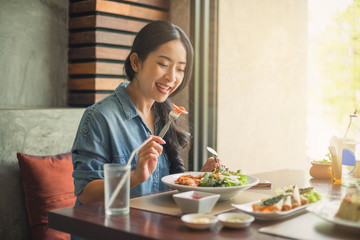 Happy woman eating healthy salad sitting on the table . Beautiful girl eating healthy food.