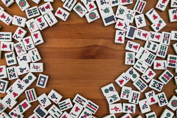 White-green tiles for mahjong on a brown wooden background. Empty place in the center.