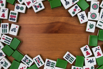White-green tiles for mahjong on a brown wooden background. Empty place in the center.