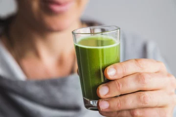 Crédence de cuisine en verre imprimé Jus Healthy woman drinking shot of wheatgrass juice