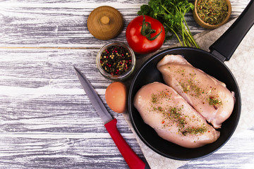 raw chicken fillet with spices in a frying pan
