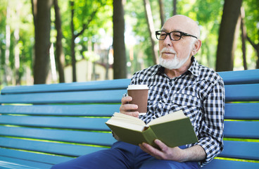 Fototapeta premium Elderly man in casual reading outdoors