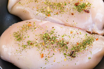 raw chicken fillet with spices in a frying pan