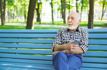 Fototapeta premium Happy senior man in earphones outdoors