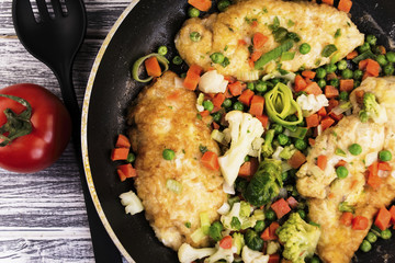 fried chicken fillet with spices in a frying pan and vegetables