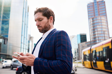 Young businessman sending text messages while standing in the city 
