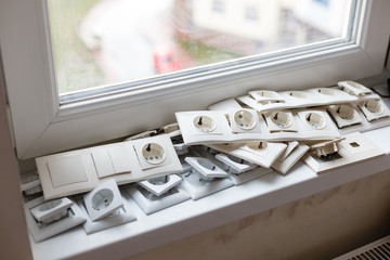 Fototapeta na wymiar Tv coaxial sockets and the stack of socket frames on the light windowsill