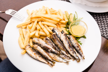 Fried sardines and fries chips on a plate in a restaurant