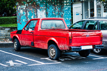 Red retro car in poor technical condition is parked in a taxi parking place.