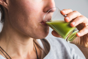 Woman drinking green wheatgrass juice shot