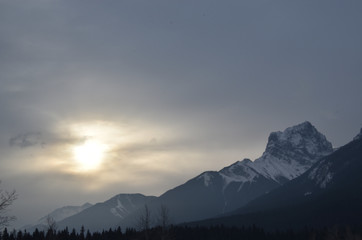 Sunlight being blocked by clouds over snowy mountain peaks