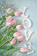 The word "love" and tulips flowers on a blue background for a Valentine's Day. 