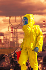 View of nuclear power plant and firefighter in a chemical protective hazmat
suit next the demaged car.
