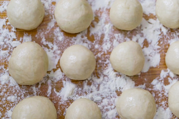 Closeup of ball ready dough on floured kitchen table. Defokus in the background.