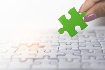  woman hand holding piece of jigsaw puzzle in green, concept of business teamwork,unity, successful background