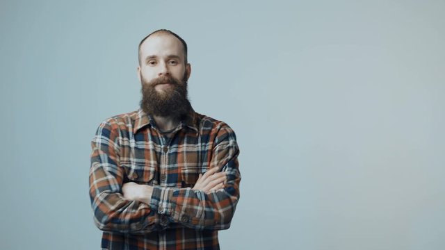 Bearded man entering in frame, smiling at camera with folded hands and gesturing OK sign