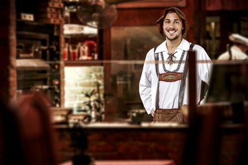 young slim man in bavarian clothes and his own small business of bar 