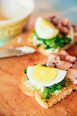 bruschetta, appetizer, canapes: fish tuna and spinach on toast of white bread, with egg on wooden Board