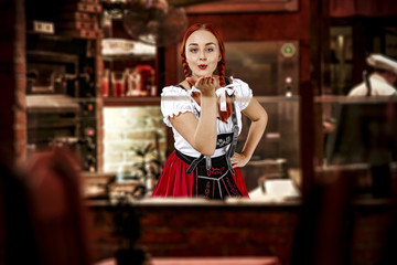 Young slim woman in bavarian clothes and her small business of bar 