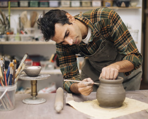 Young man making pottery in workshop