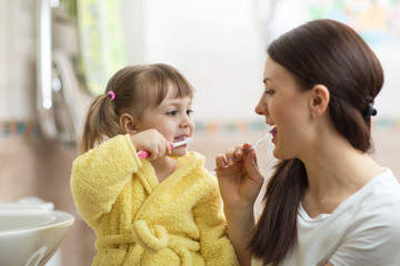 Mother teaches her little daughter teeth brushing