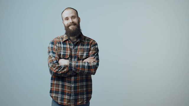 Bearded man entering in frame, smiling at camera with folded hands and gesturing thumb up sign