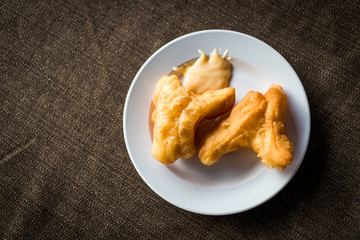 Flat lay deep fried dough stick in the plate on table.