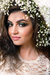 Caucasian attractive woman closeup with lilies on head on white roses wall. Spring concept