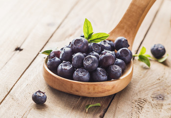 Blueberry in wooden spoon on rustic background.