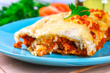 Traditional Italian pasta cannelloni. Baked tubes stuffed with minced meat with parmesan cheese and bechamel sauce on a white wooden table.