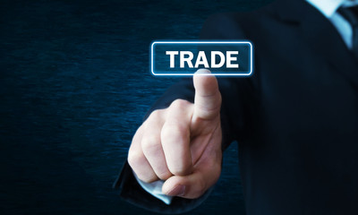Man hand clicking Trade button on screen.