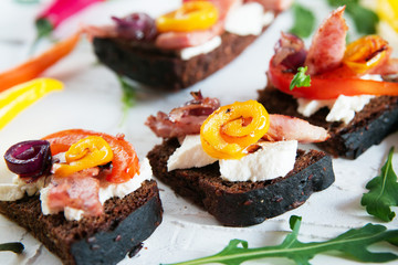 tasty appetizer, Toast with stuffing, appetizer, canapés: tomato and pepper grill, soft cheese, meat, Italian herbs, whole wheat bread.
