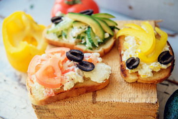 Variety of vegetarian bruschetta with fresh vegetables: toast, tomatoes, pepper, avocado, greens. The concept of healthy eating, vegetarianism.