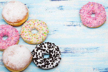 Traditional donuts on white wooden background.  Tasty doughnuts with icing and powdered sugar, copy space