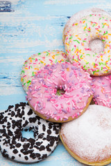 Traditional donuts on white wooden background.  Tasty doughnuts with icing and powdered sugar, copy space