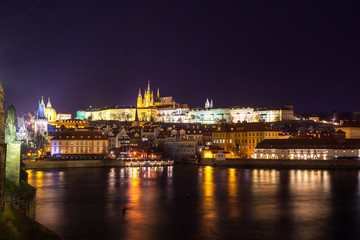 Fototapeta na wymiar Night view of Prague in color lights: ancient historic buildings and St. Vitus Cathedral, Czech Republic