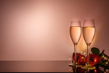 Champagne glasses, present and roses in front of beige background