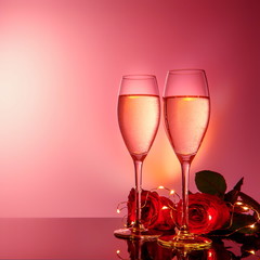 Champagne glasses, present and roses in front of beige background