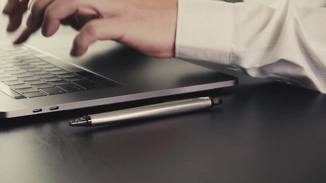 Businessman working with laptop computer on wooden desk in slow motion