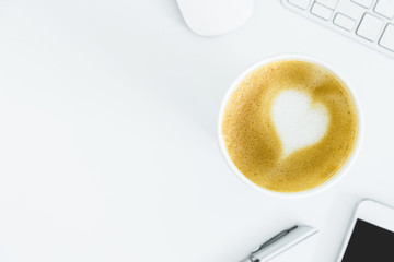 A latte coffee with art heart milk on the white desk table from top view and copy space. Flat lay with desk, business and valentine concept.