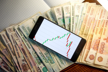 money. russian ruble. smartphone with exchange rates screen is on the notebook