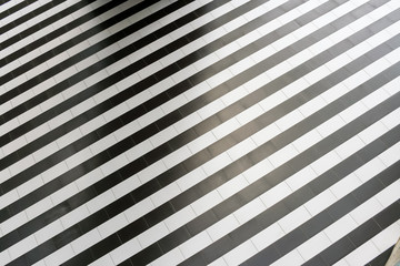 Abstract geometric pattern of regular alternating black and white stripes on the floor.