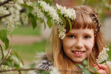 Young girl walks in the spring near a tree that blooms with white flowers