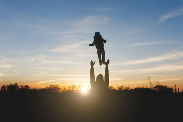 Silhouette of man high toss up little cute child baby boy on nature, sunset horizon background. Father throw up fun little kid son outdoors. Family day 15 of may, love, parents, children concept.