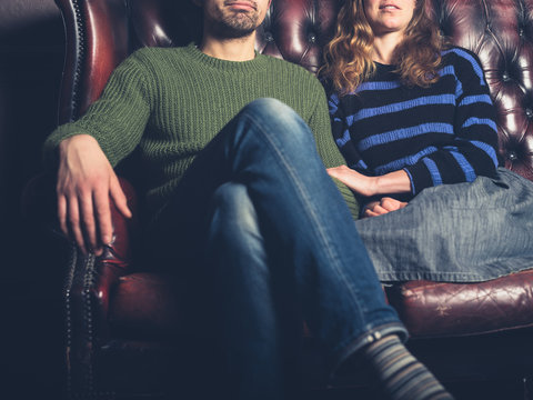 Happy young couple sitting onsofa at home