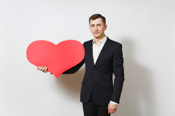 Young handsome man in suit holding big red heart isolated on white background. Copy space, advertisement. Place for text. St. Valentine's Day, International Women's Day, birthday, holiday concept.