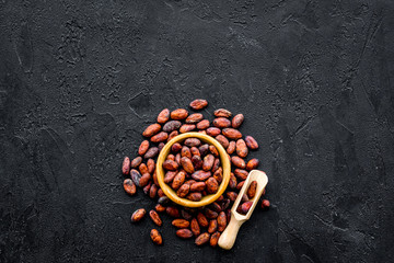 Roasted cocoa beans on black background top view copy space. Raw material for cocoa powder. African or Latin American product