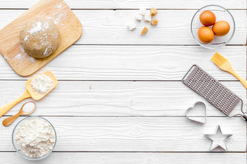 Ball of fresh raw dough near ingedients and cookware on white wooden background top view copy space